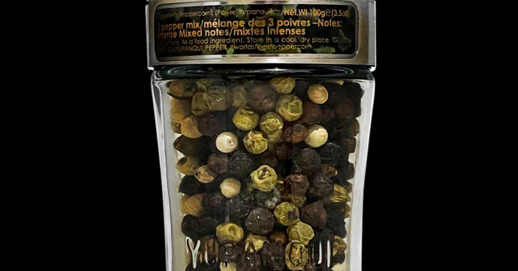 Black white and green Piper nigrum peppercorns together in a Yupanqui Camouflage grinder