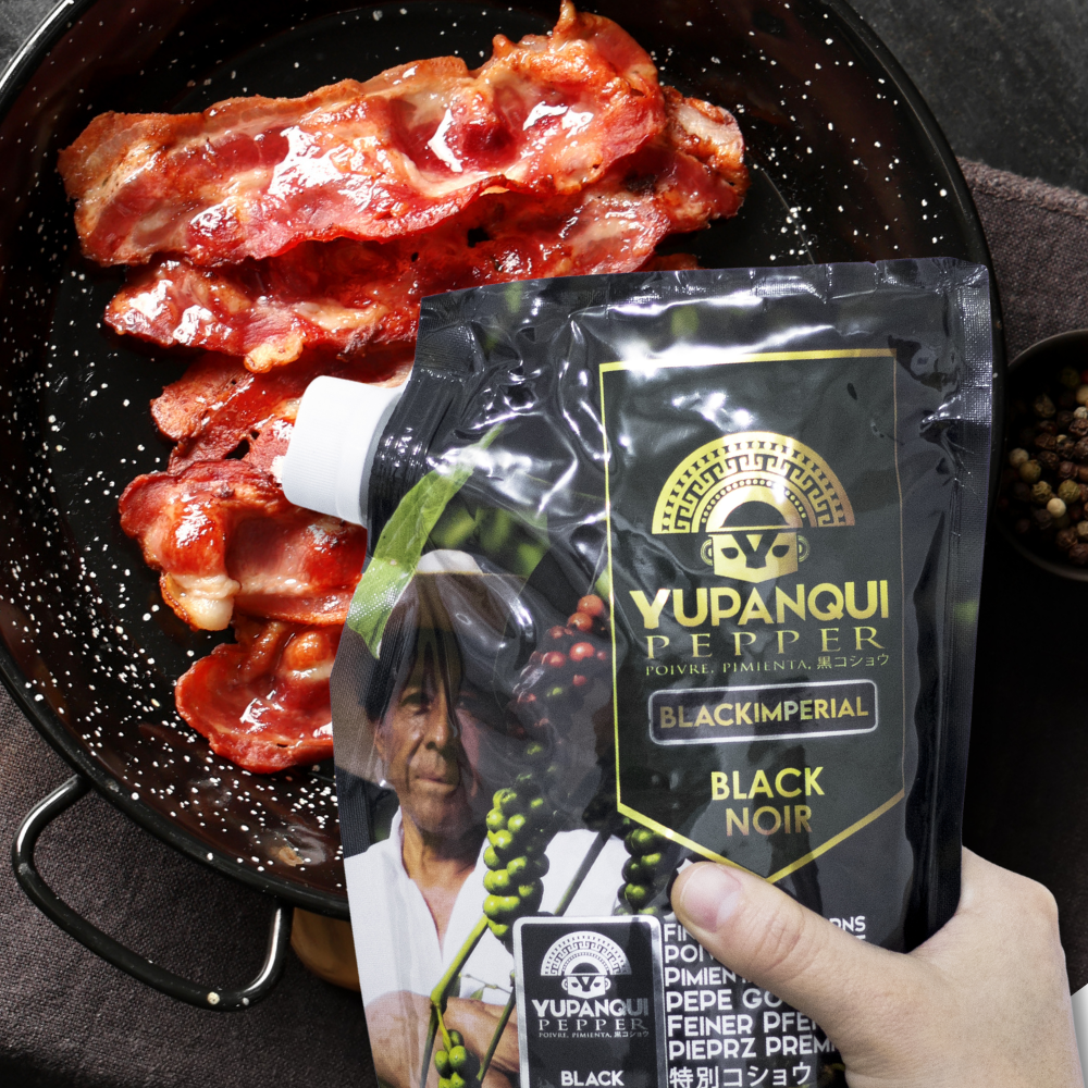 Yupanqui Black Imperial 17.6 oz peppercorn refill bag beside fresh herbs and an everyday meal